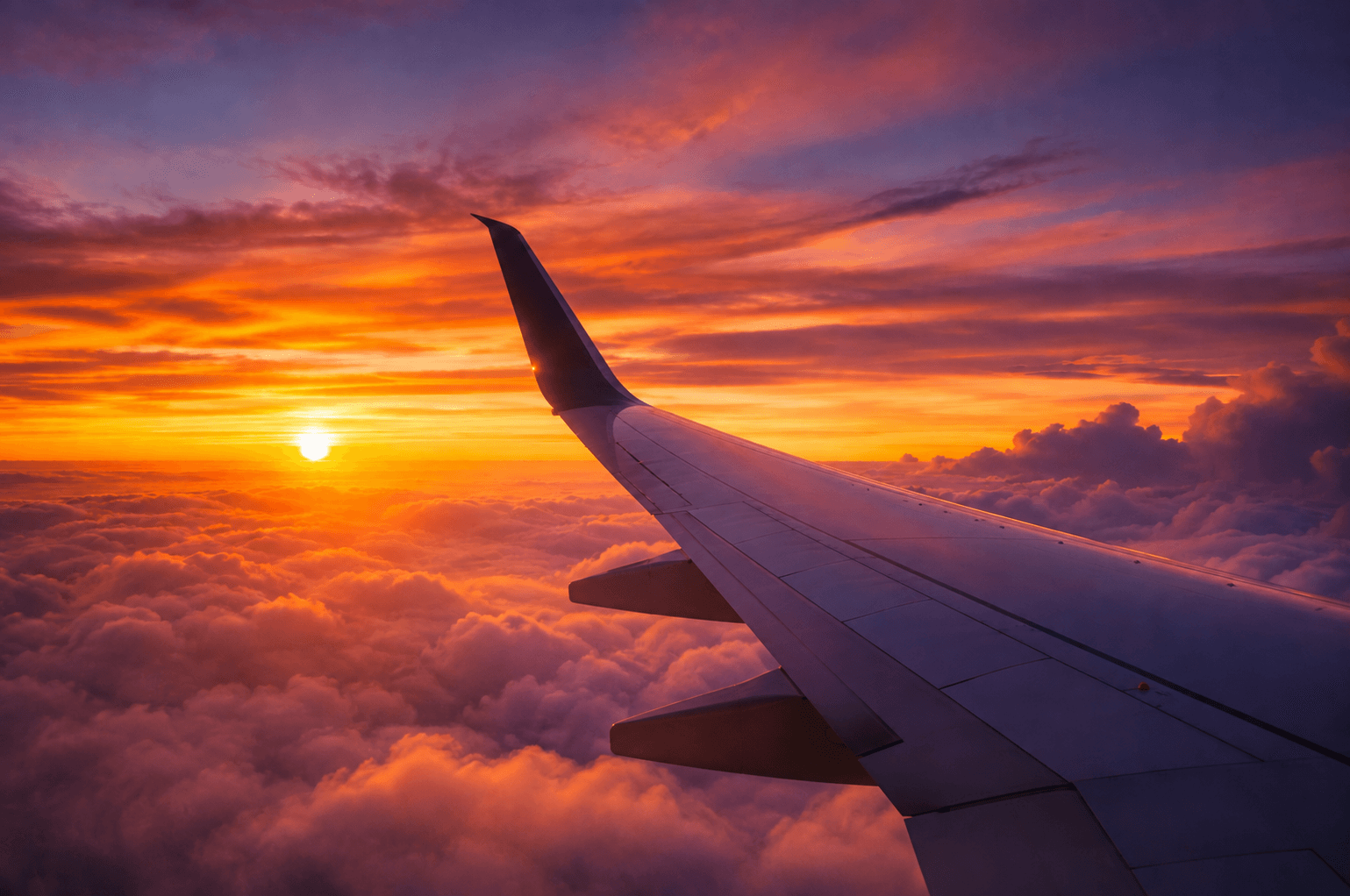 Flygplansvinge ovanför molnen i solnedgång